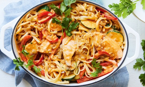 Red Curry Salmon Linguine in white dish with a blue towel and coriander