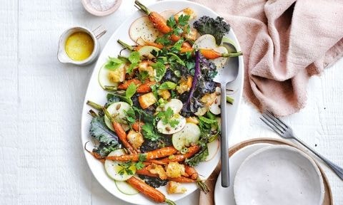 Roasted carrots, radish, pear, kale and herbs served on a plate