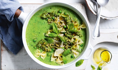Green Pesto Vegetable Soup in white dish. Olive oil in a glass jug and a white towel.