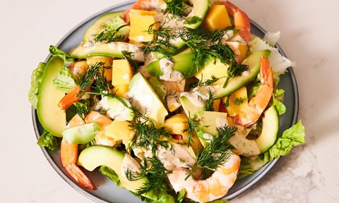 A bowl of prawn salad served with avocado and dill