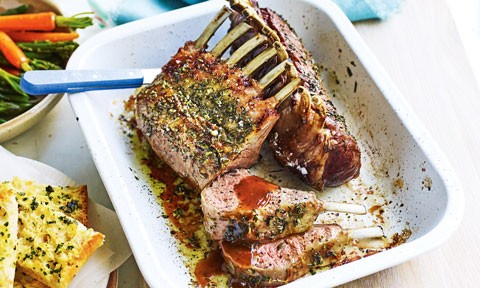 A baking dish with a rack of roast lamb covered in a rosemary rub
