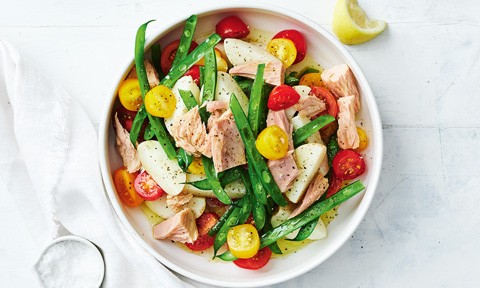 A bowl of tuna salad with beans, tomatoes and lemon