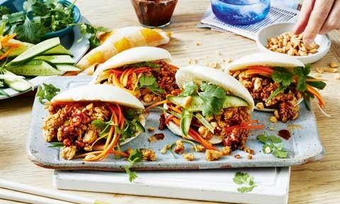 A plate of chicken bao buns packed with mince, cucumber, carrot, coriander and peanuts.