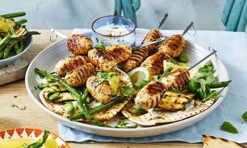 A bowl of chicken kofta skewers with green beans and pita bread.