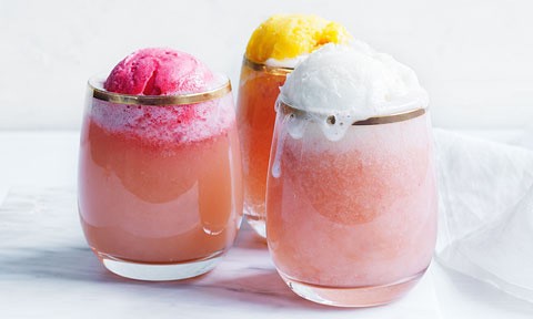 Three glasses of white peach and prosecco float with scoops of lemon, mango and berry sorbet.