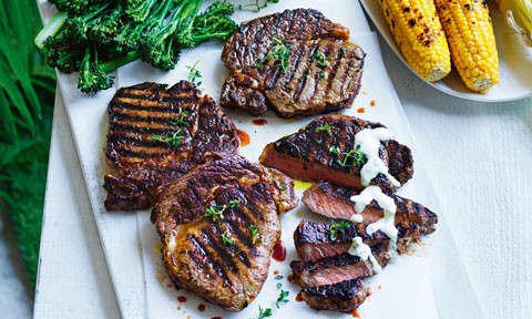 Four BBQ steaks with creamy lemon sauce and corn on the cob