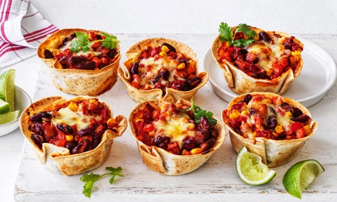 Six mexican-style mini pies topped with coriander sprigs