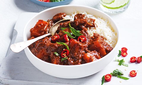 Beef vindaloo served in a bowl with rice and mint and chilli on top
