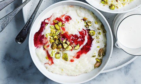 Rice pudding in a bowl with berry compote and pistachios