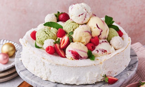 pavlova topped with lots of berries and assorted ice cream flavours