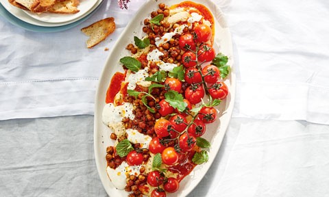A tray of loaded hommus topped with chickpeas and roast tomatoes