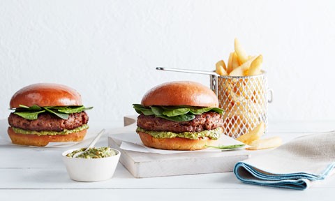 Beef and Thyme Burgers on a chopping board, with a side of chips and extra dip in a bowl