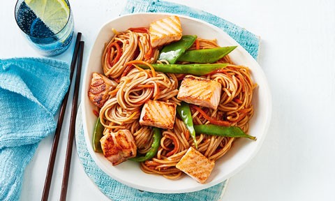 Salmon chunks served in a bowl with noodle stir-fry and snow peas 