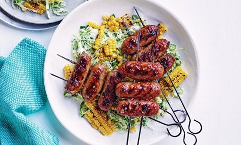 Sausage skewers served with coleslaw and corn