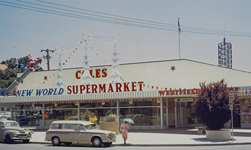 1960s photo of outside of Coles supermarket with Christmas decorations on the shop front