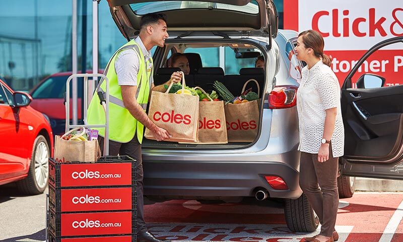 Coles employee putting groceries in a car boot