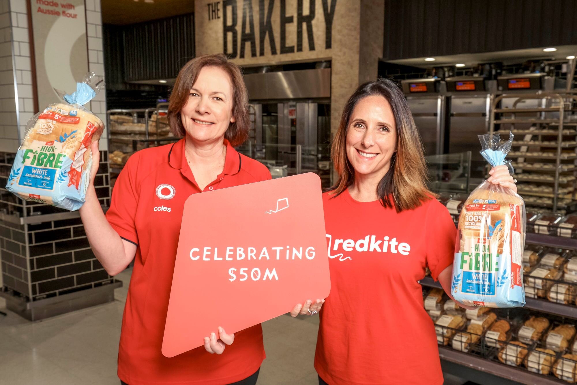 Coles employees holding bread with redkite sign with words celebrating 550M