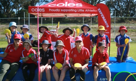 Children and trainers sitting on a high jump mat