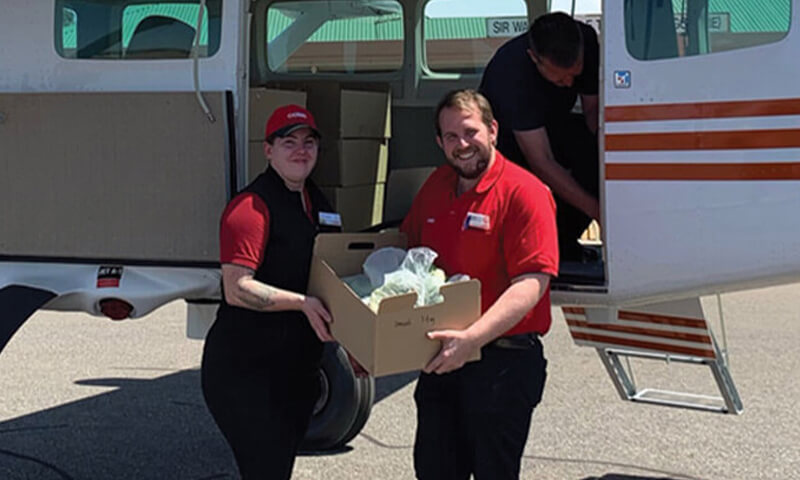 Coles team members loading boxes into a plane