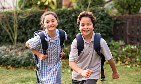 Kids running in School uniforms with backpacks on outside