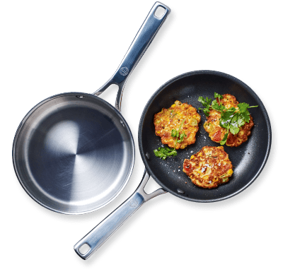 Two MasterChef frying pans one with fritters and herbs in it