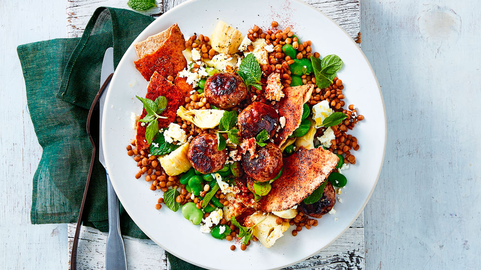 A dish of artichoke and lentil salad with meatballs