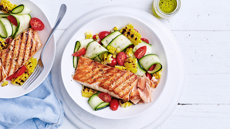 Barbeque Salmon with served in two dishes on top of corn, zucchini and tomato salad