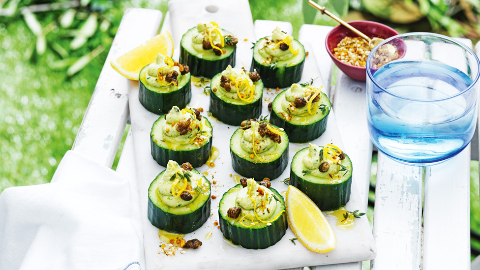 Ten cucumber bites with two lemon wedges on the side.