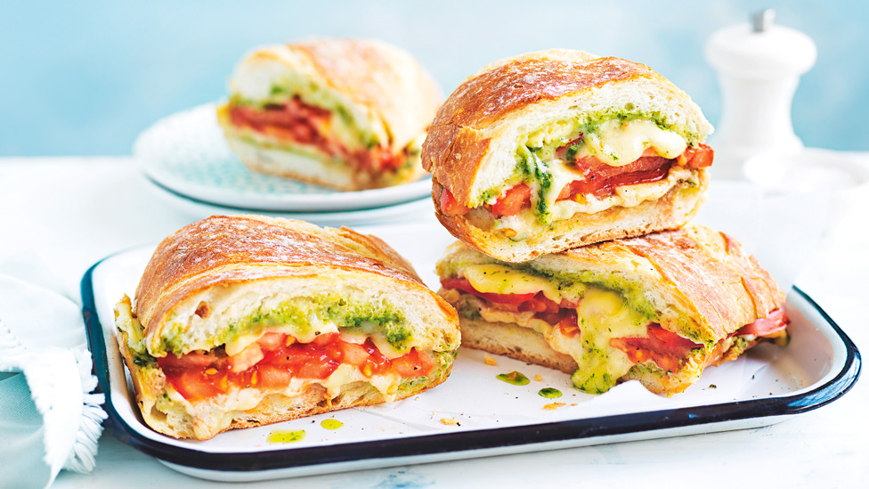 Four toasted cheese sandwiches with basil and tomato