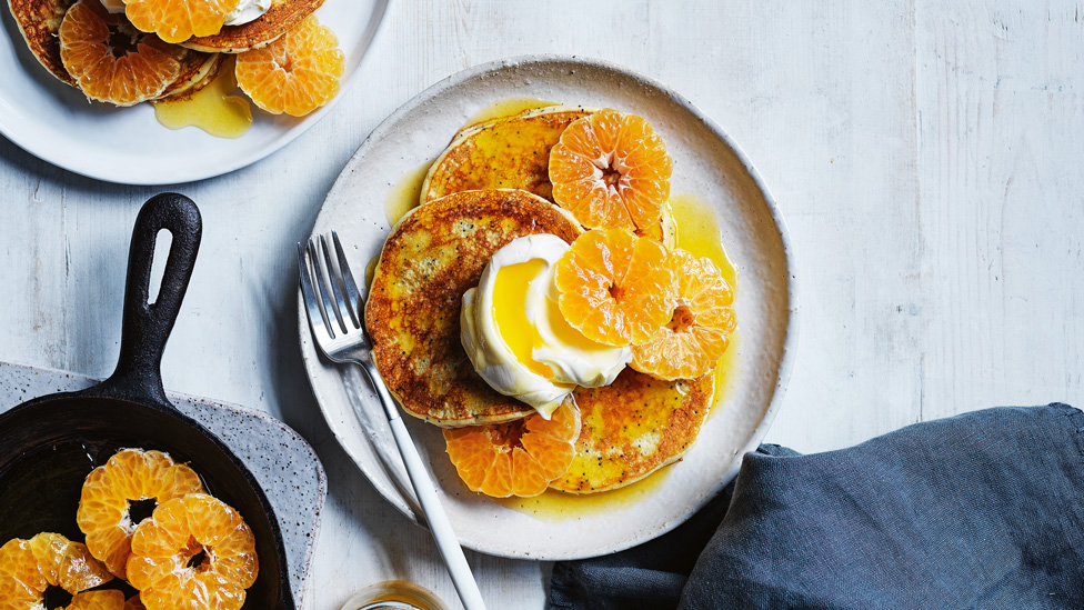 Lemon poppyseed pancakes topped with whipped cream and sliced mandarins