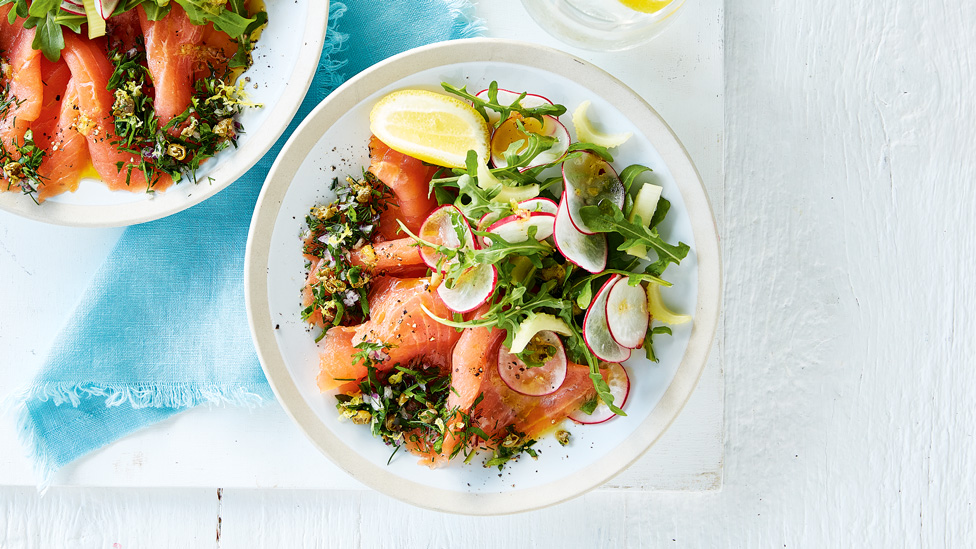Two bowls of smoked salmon carpaccio with oil and salad.