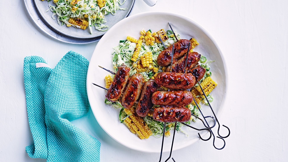 Sausage skewers served with coleslaw and corn