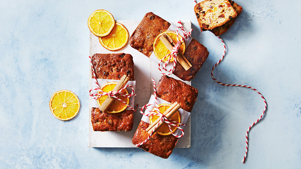 Three fig, apricot and pistachio fruitcakes decorated with dried orange and cinnamon sticks