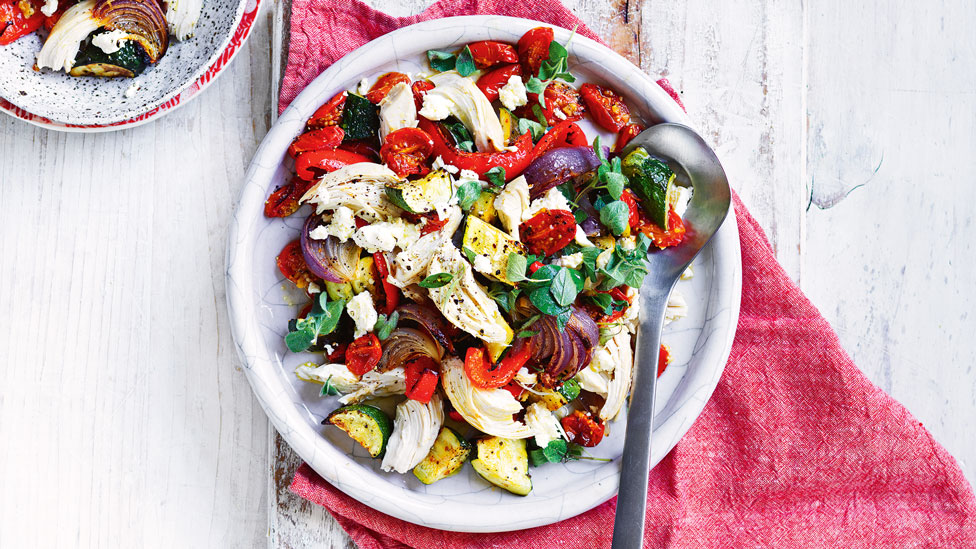 Chicken, red capsicum, red onion and zuccini salad served in a plate and a bowl with a serving spoon on the plate