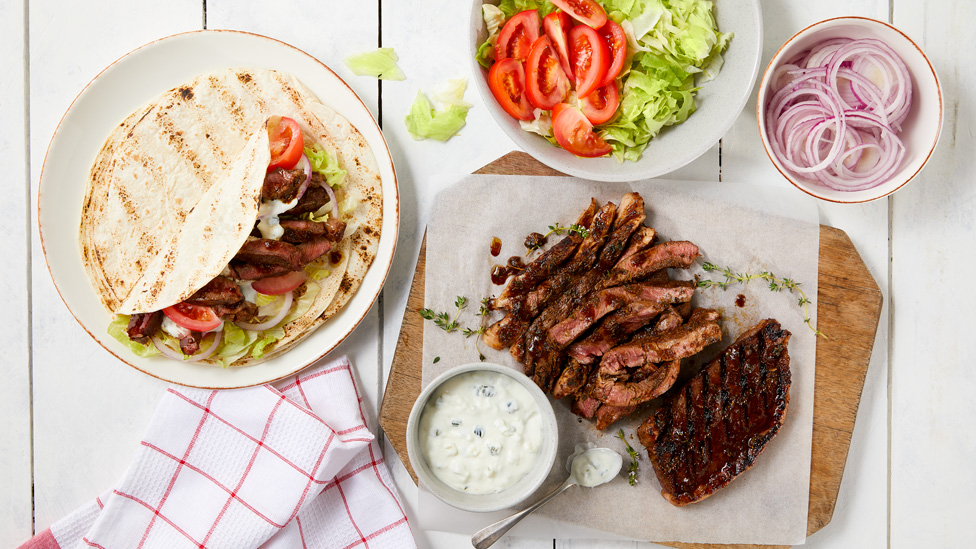 Grilled beef wraps with thickly sliced beef, lettuce, tomato, onion and tzatziki dip