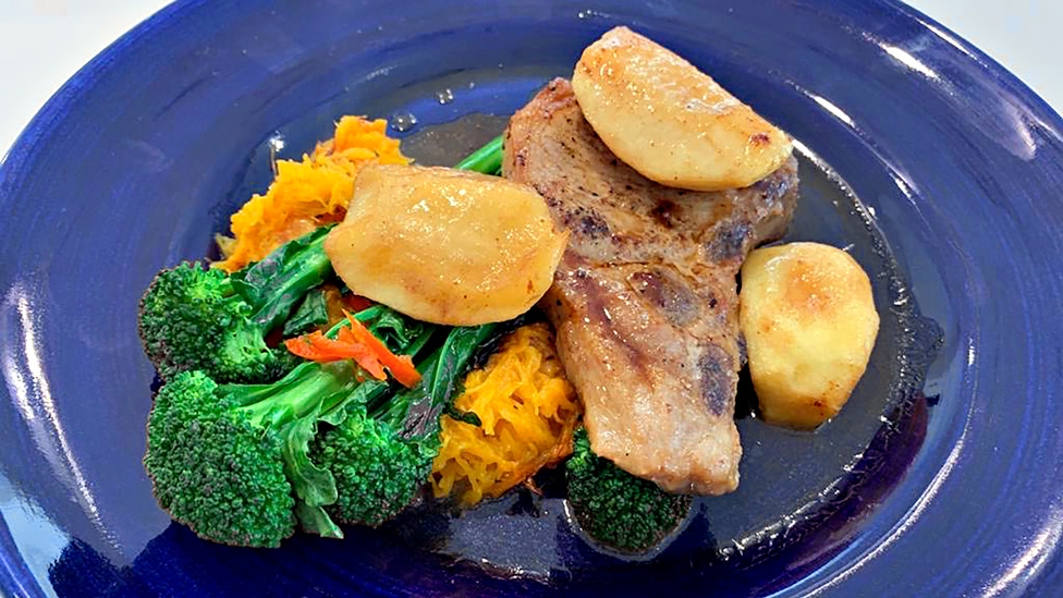A plate of pork chops with roasted vegetables.