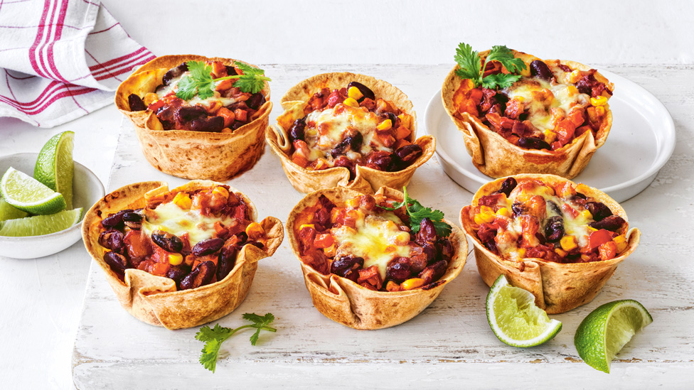 Six mexican-style mini pies topped with coriander sprigs