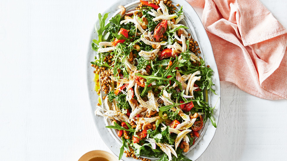 Chicken and lentil salad with rocket served in a large dish with olive oil dressing beside
