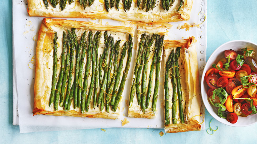 Ricotta and asparagus tarts cut in large pieces, served with tomato and rocket leaves