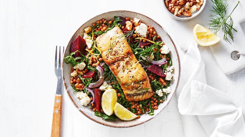 Barramundi served on top of silverbeet, lentil and fetta salad with a lemon wedge as a garnish 