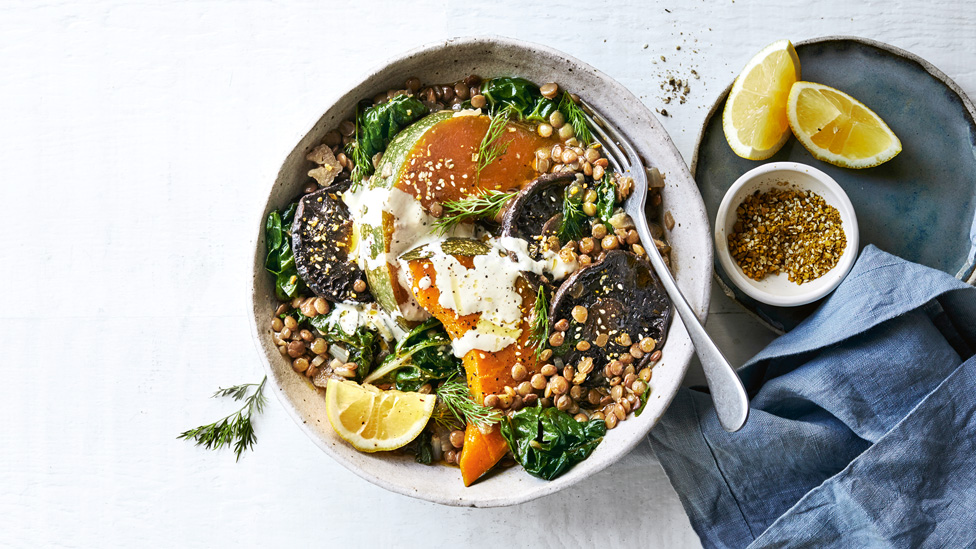 Lentil and veggie stew bowl with lemon wedges and dukkah