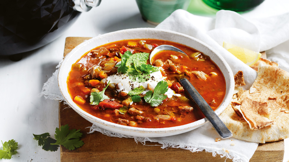 Slow Cooker Spiced Chicken and Chickpea Soup in bowl, garnished with yoghurt and coriander. Served with pita bread