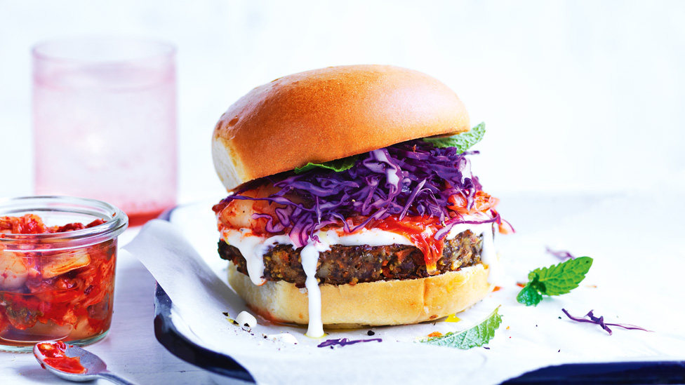 Close up of veggie and kimchi burger with purple cabbage and mint garnish