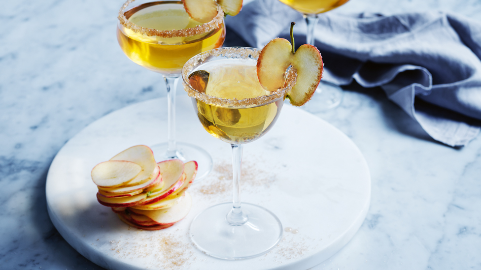 Glass of warm apple pie martini with apple slices.