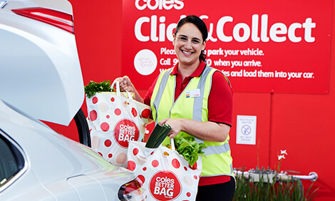 Coles employee putting grocery bags in the boot of a car