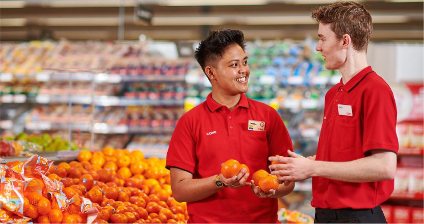 Team members in store smiling holding fruit