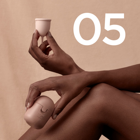 A lady holding an organic period cup and its case with number 5 featured
