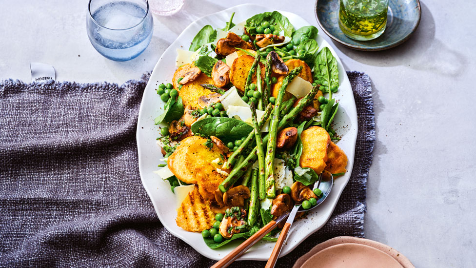Mushroom and spring vegetable salad with crostini on oval plate