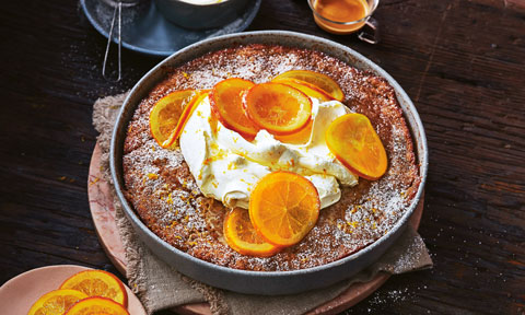 A dish of butterscotch pudding topped with orange slices and whipped cream.