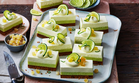 A tray of ginger and key lime slice bars topped with fresh lime and crystallised ginger.